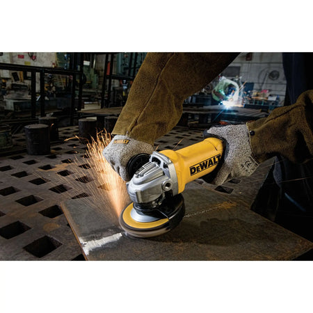 A wide action shot of a professional welder using the DEWALT DWE402 grinder on a heavy steel plate. A stream of sparks demonstrates the aggressive material removal rate of the 11-Amp motor in a fabrication shop environment.