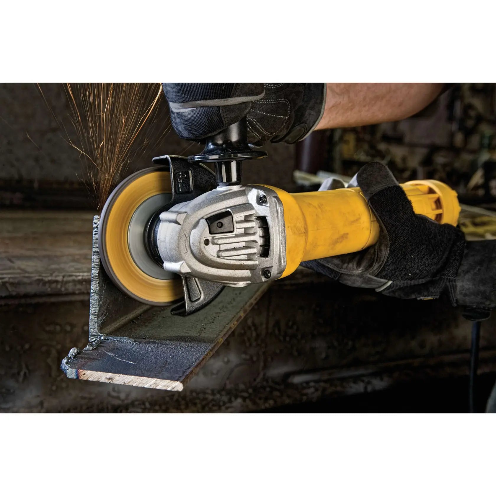 A detailed action view of the DEWALT DWE402 blending a vertical weld on a steel L-beam. The photo highlights the compact head design and the visibility provided to the user during precision industrial grinding and finishing.