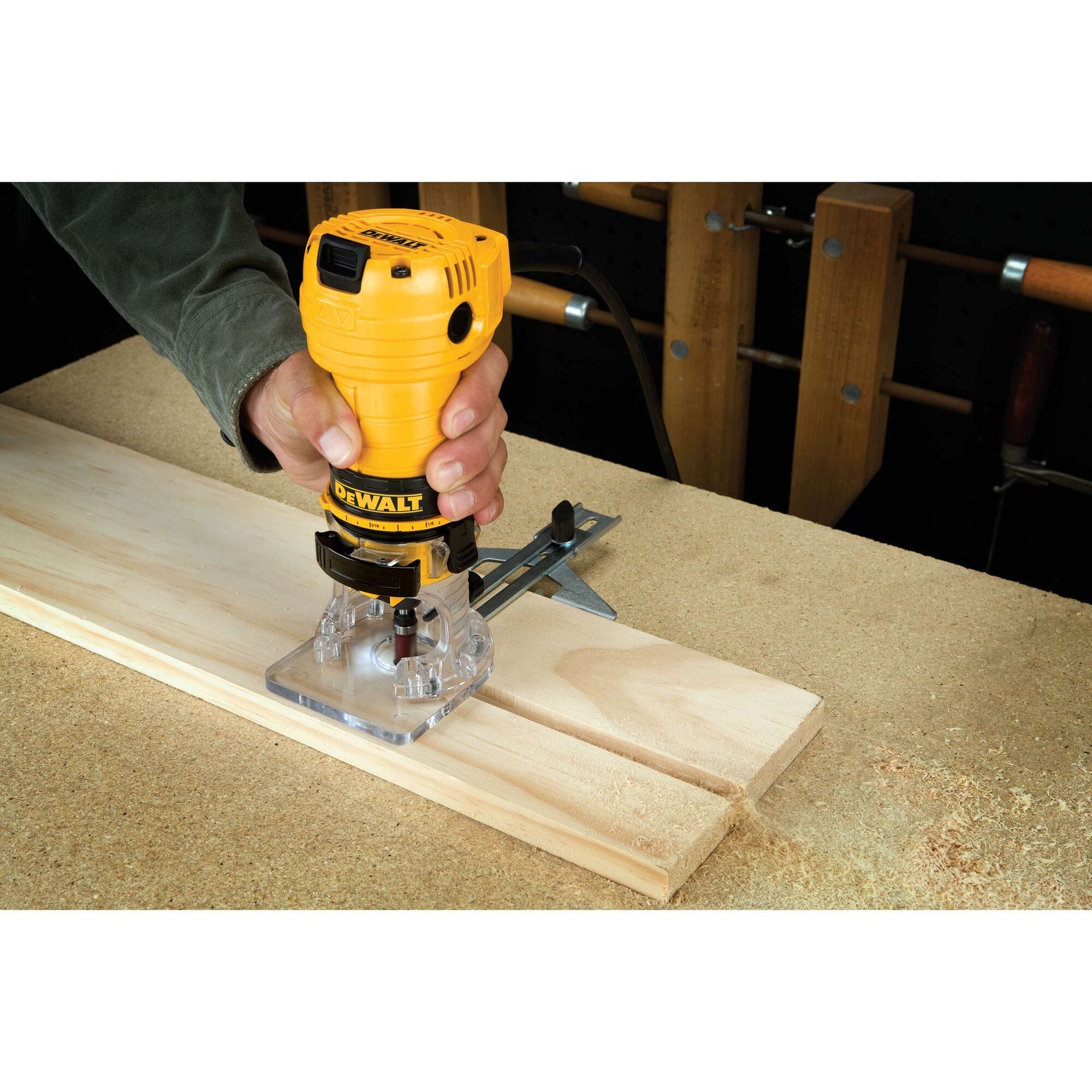 A woodworker using the DEWALT DWE6000 1/4 Inch Laminate Trimmer with the included straight edge guide to rout a precise groove into a wooden board, demonstrating stable single-handed control.