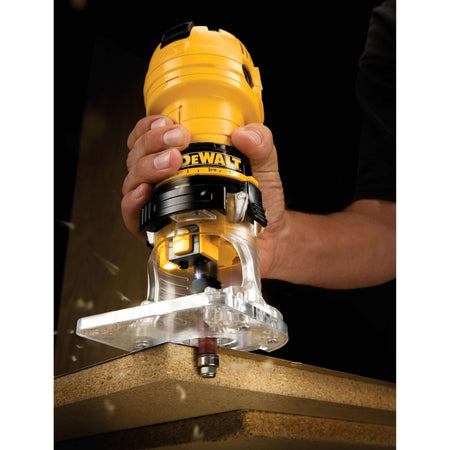 Action shot of the DEWALT DWE6000 4.5 Amp Laminate Trimmer routing the edge of a laminate countertop, showcasing the high-visibility LED light and ergonomic grip in a professional woodworking application.