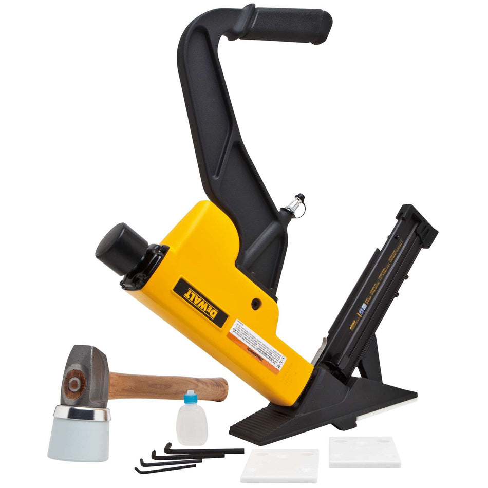A complete product kit view of the DEWALT 2-in-1 flooring tool including the pneumatic nailer and stapler, a white-capped flooring mallet, maintenance oil, adjustment wrenches, and interchangeable base plates for various hardwood thicknesses.