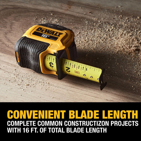 The DEWALT 16-foot ATOMIC tape measure sitting on a wooden work surface with the blade extended, emphasizing its 16' length suitable for common professional construction projects.