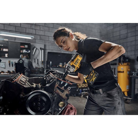Automotive mechanic using a DEWALT deep impact socket attached to a 20V cordless impact wrench to perform heavy duty repairs on an exposed engine block.
