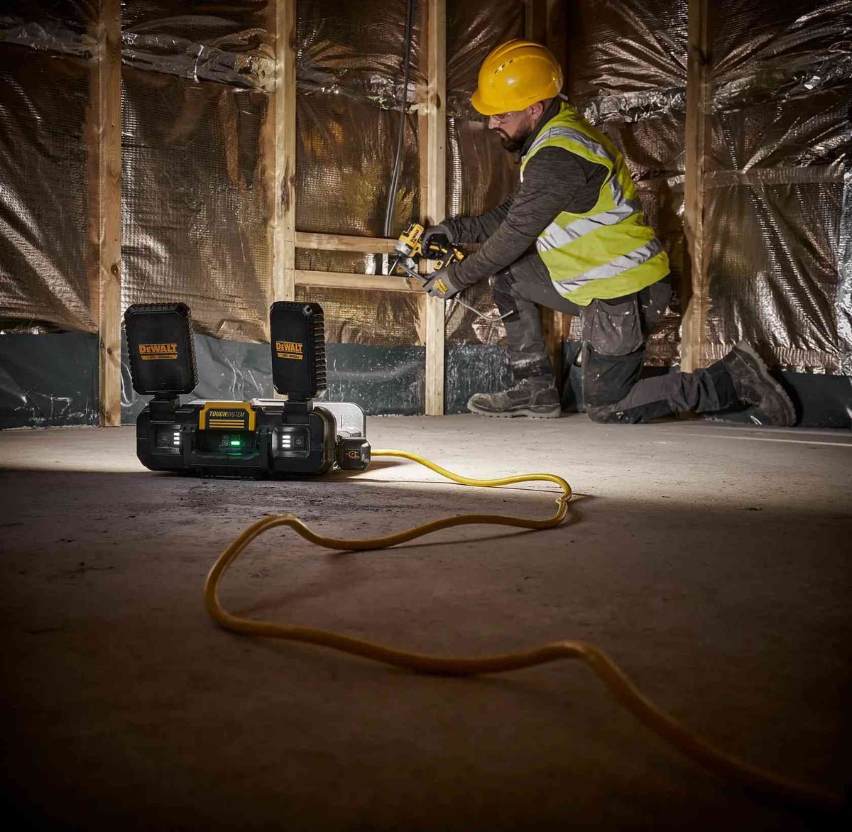 DEWALT ToughSystem 2.0 hybrid work light powered by a yellow extension cord, illuminating an interior construction framing project for a professional worker.