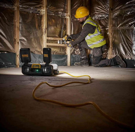 DEWALT ToughSystem 2.0 hybrid work light powered by a yellow extension cord, illuminating an interior construction framing project for a professional worker.