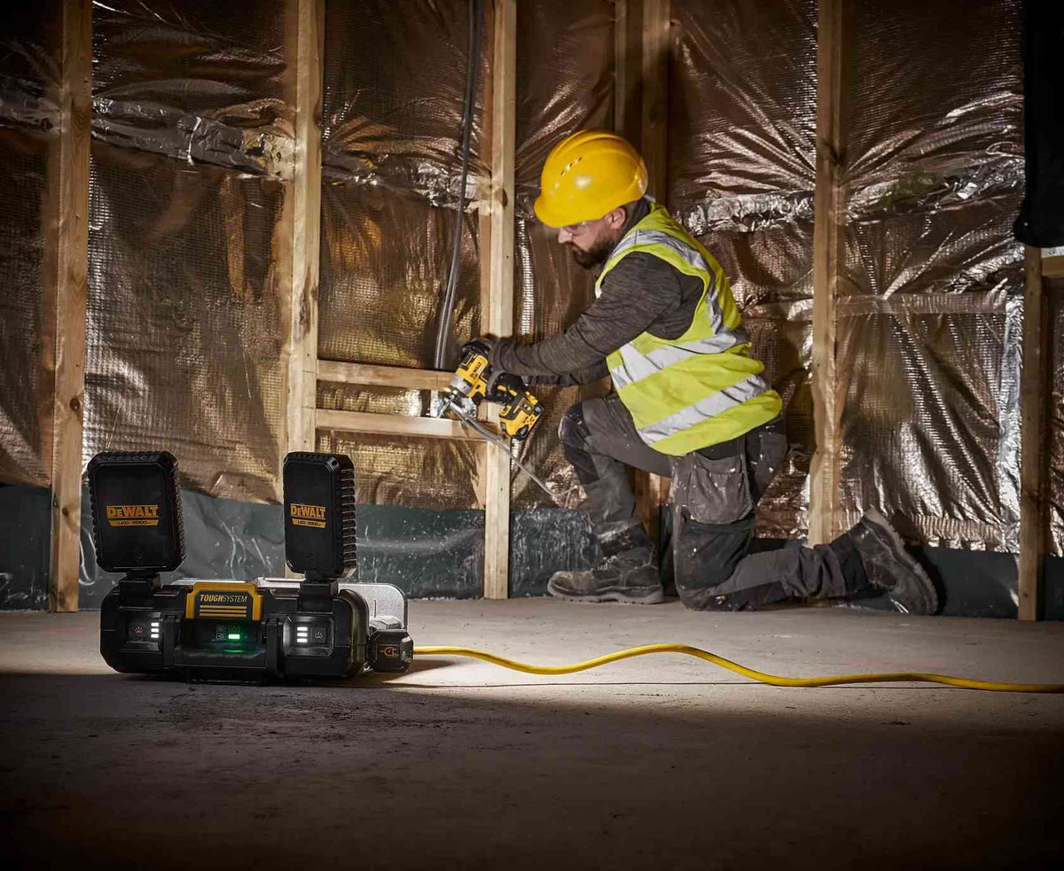 DEWALT ToughSystem 2.0 work light used freestanding on a concrete floor to provide bright, natural white light for a contractor performing wall installations.