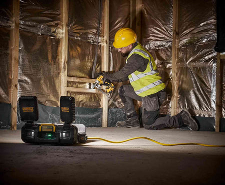DEWALT ToughSystem 2.0 work light used freestanding on a concrete floor to provide bright, natural white light for a contractor performing wall installations.