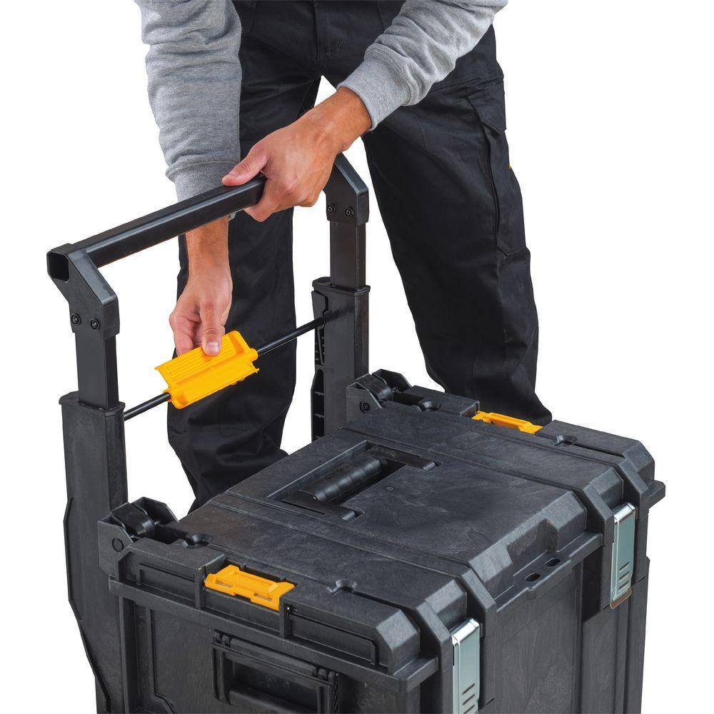 Close-up action shot of a professional contractor engaging the patented auto-connect side latches to secure the DEWALT large tool box to a rolling workshop system.