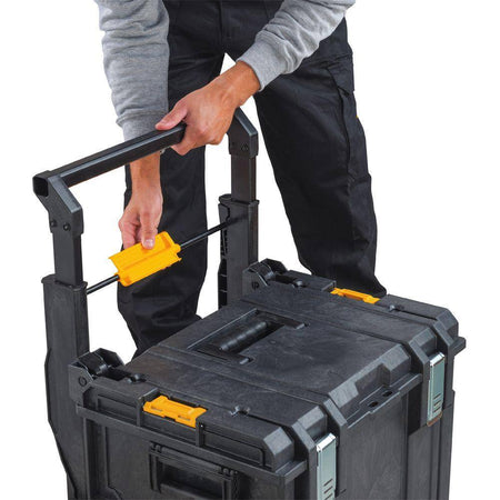 Close-up action shot of a professional contractor engaging the patented auto-connect side latches to secure the DEWALT large tool box to a rolling workshop system.