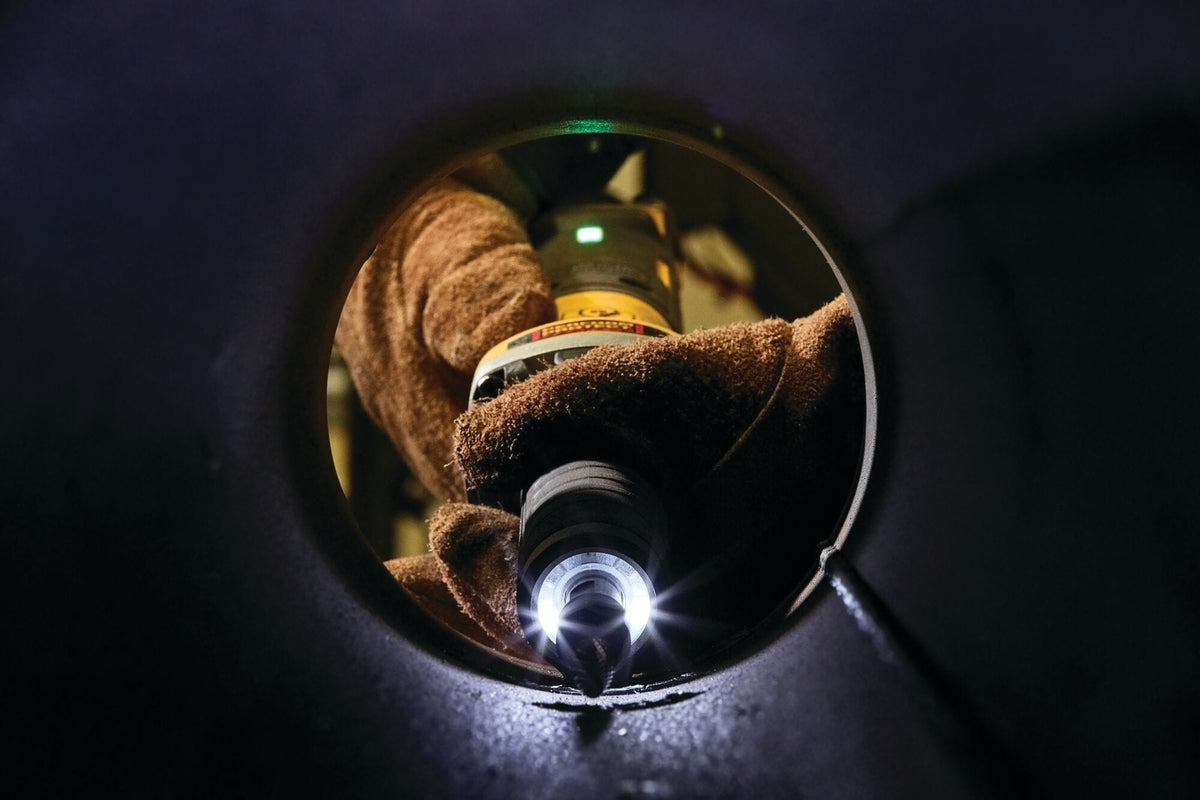 Close‑up view of a technician using a DEWALT DWE4997VS die grinder through a circular metal opening, performing detailed internal grinding and precision finishing on steel.