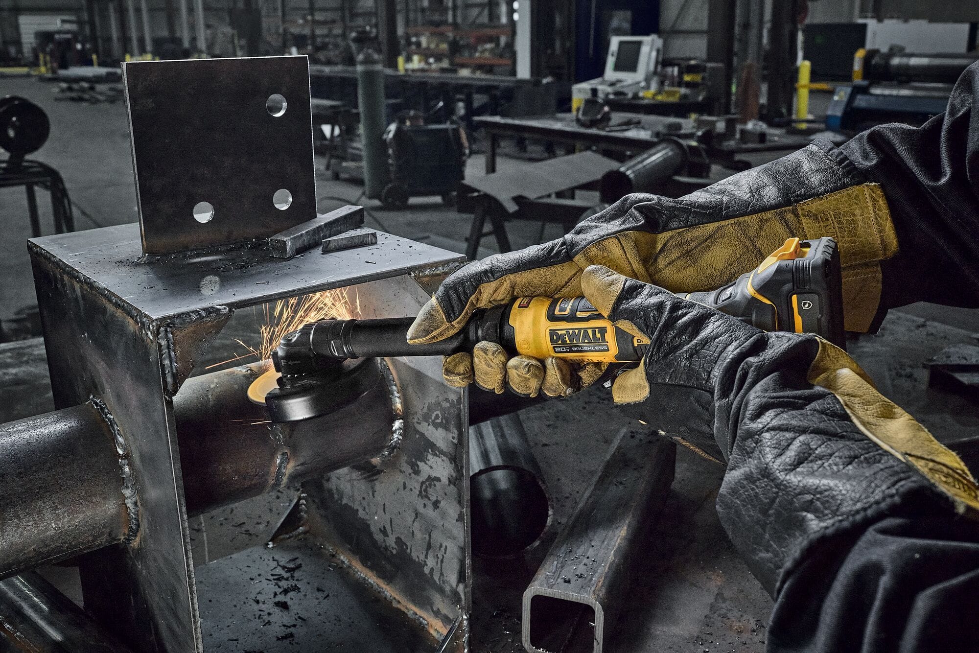 Professional metalworker wearing heavy leather gloves using the DEWALT DCG432XGE2 20V MAX 4 inch extended cut-off tool to slice through a steel pipe, demonstrating narrow space cutting capabilities with flying sparks.