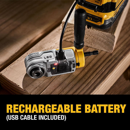 The DEWALT DWALRAMF attachment resting on a wood surface while charging via the included USB cable, with a red indicator light showing the charging status.
