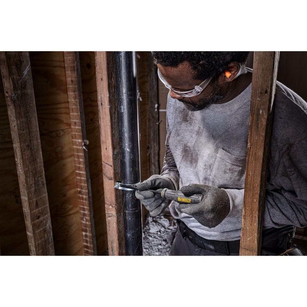Action shot of a professional tradesman using a DEWALT demo screwdriver to pry a metal pipe strap in a residential framing environment, demonstrating the tool's high-torque prying capability.