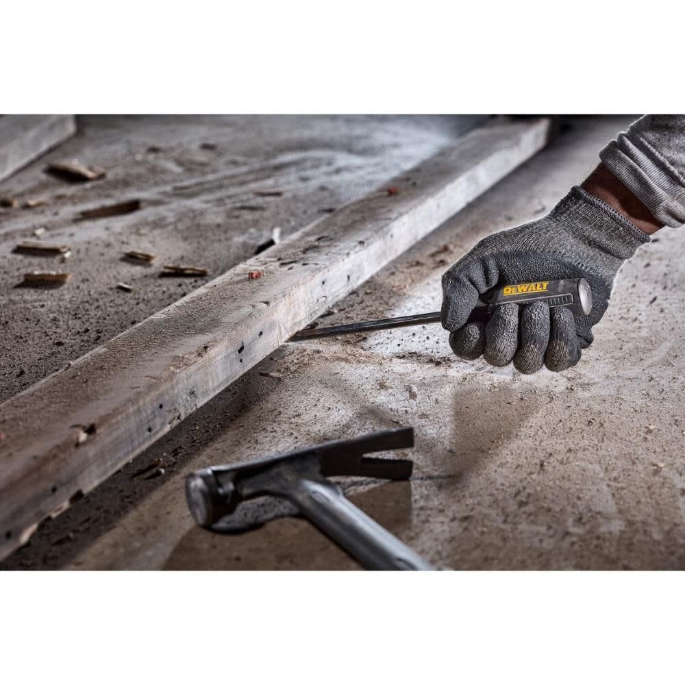 Close-up of a worker using a DEWALT demolition screwdriver to pry a wooden board on a concrete floor, illustrating the heavy-impact durability and bend resistance of the S2 steel bar.