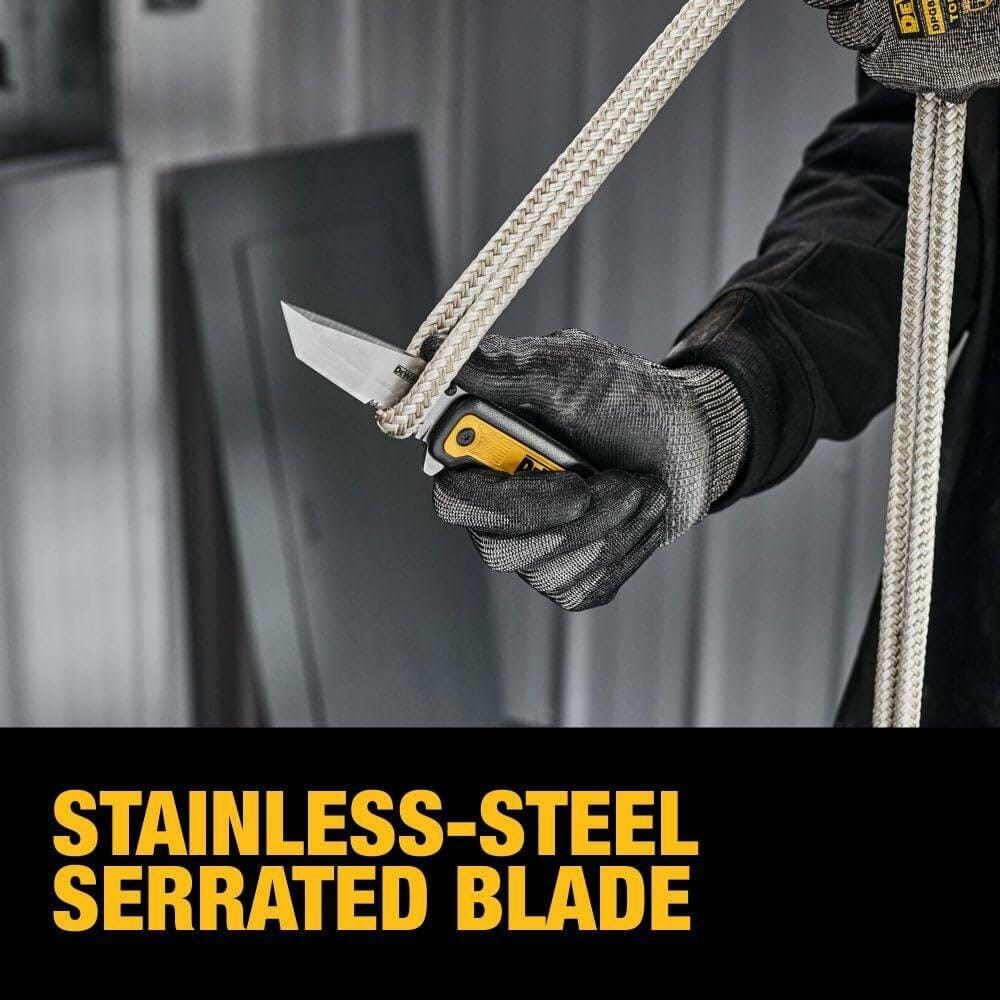 A gloved hand holding the open DEWALT Tanto pocket knife, using the stainless-steel partially serrated blade to cut a thick white rope.