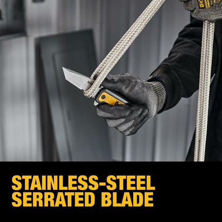 A gloved hand holding the open DEWALT Tanto pocket knife, using the stainless-steel partially serrated blade to cut a thick white rope.