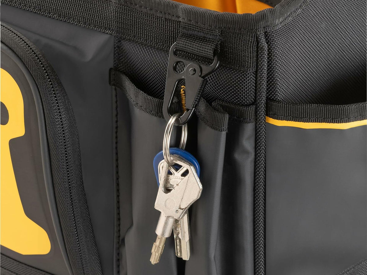 Close-up of a DEWALT tool tote with a black metal clip holding a keyring with three keys. The clip is attached to an exterior loop, demonstrating secure storage for personal items. The bag features durable fabric and multiple compartments.