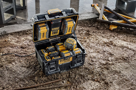 A detailed lifestyle shot of the DEWALT ToughSystem 2.0 charging station sitting on wet ground. This view emphasizes the effective weather-resistant seals and the internal LED indicators that allow users to monitor battery charge levels in real-time during outdoor use.