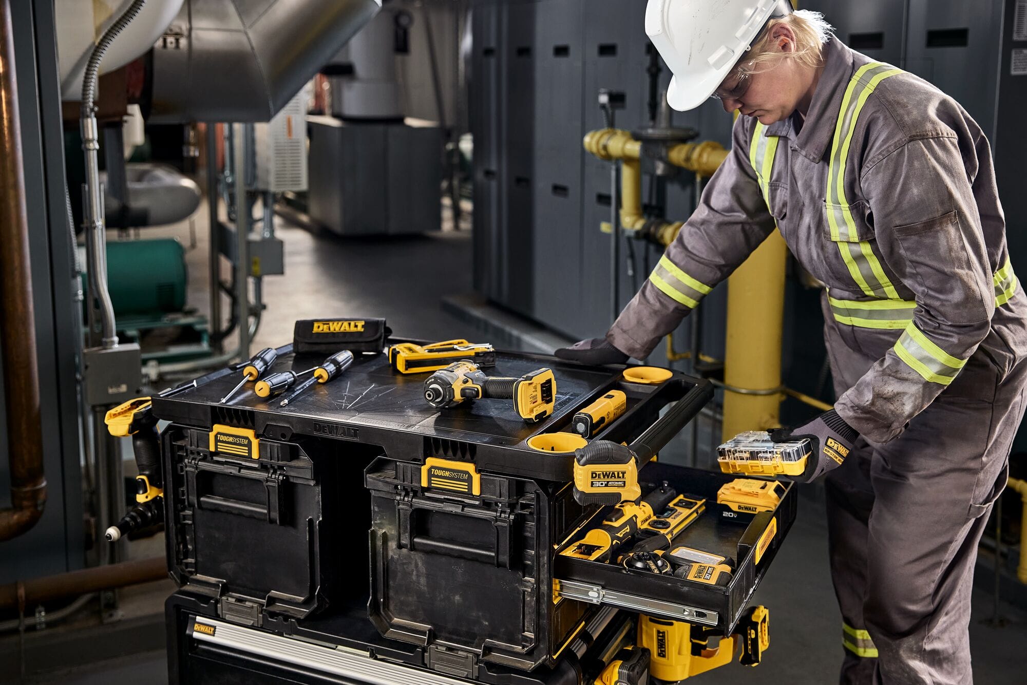 Worker standing beside a fully stocked DEWALT ToughSystem storage station containing drills screwdrivers flashlights and accessories organized in multiple drawers for industrial maintenance tasks.