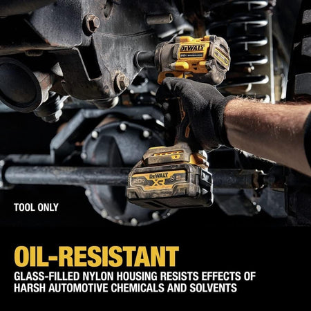 Person using DeWalt cordless impact wrench under a vehicle, highlighting oil-resistant glass-filled nylon housing suitable for harsh automotive environments