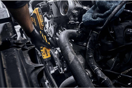 Person using a DEWALT cordless ratchet wrench to tighten a bolt inside a car engine bay, showcasing the tool’s compact design and automotive application.