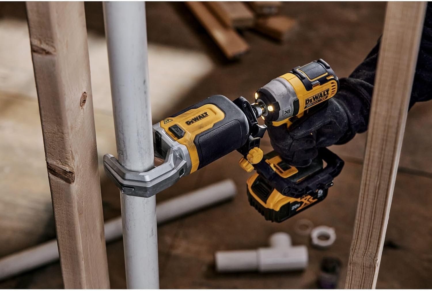 Person using a DEWALT 20V MAX XR impact driver with a right-angle attachment to fasten a bolt on a metal pipe in a tight space between wooden studs.