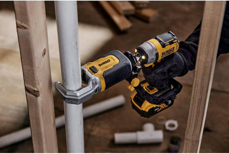 Person using a DEWALT 20V MAX XR impact driver with a right-angle attachment to fasten a bolt on a metal pipe in a tight space between wooden studs.