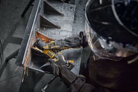 Overhead action view showing an operator wearing protective leather welding gloves and a safety helmet utilizing the DeWalt 20V MAX cordless 3-inch cut-off saw to execute precision linear cuts on tight interior channels inside a custom structural steel storage bin layout, throwing off bright sparks