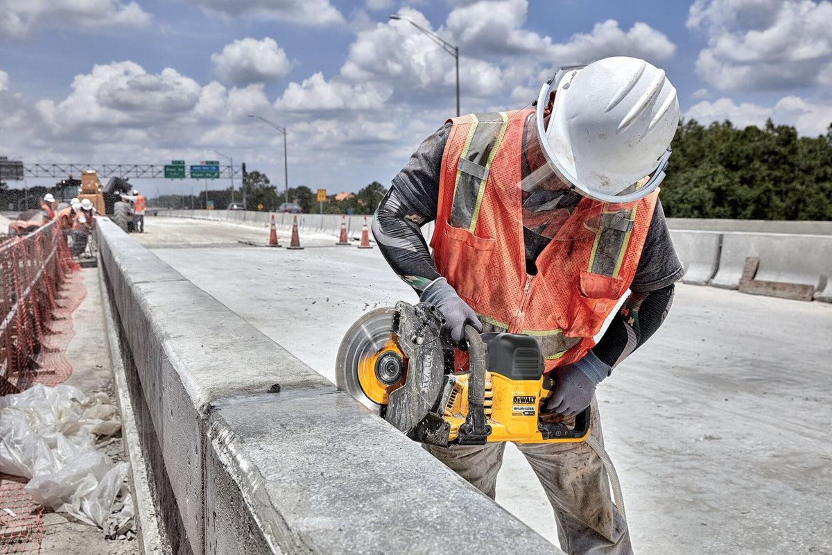 Worker scoring highway concrete using the DeWalt 9-inch cut-off saw with water feed to suppress silica dust.