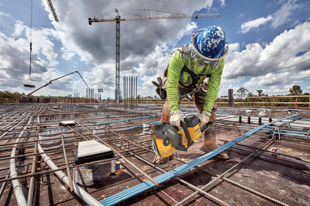 Ironworker using the DeWalt 60V power cutter to slice post-tension cables across an elevated concrete deck.
