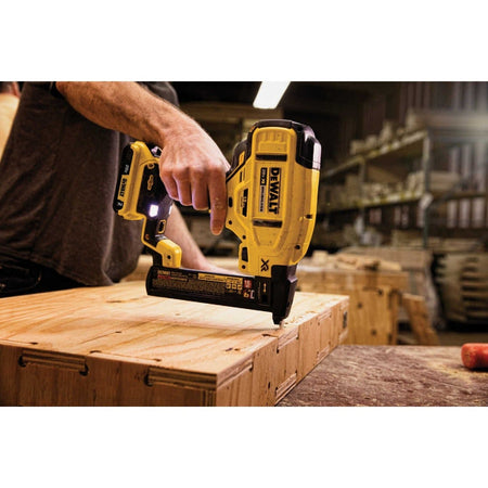 An action shot of a worker using the DeWalt DCN681 cordless stapler to fasten a piece of plywood.