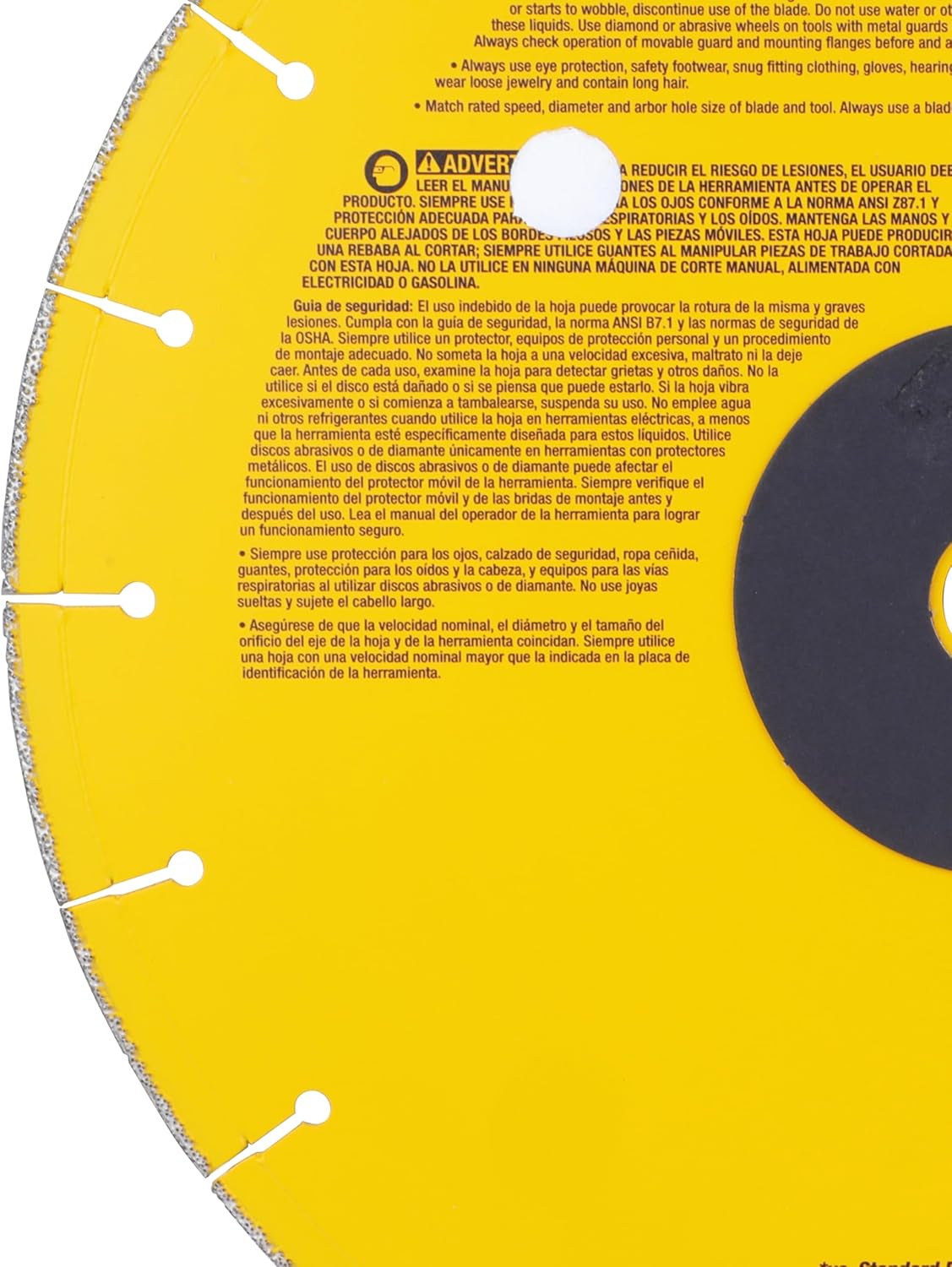 A detailed close-up view of the rear left quadrant of the DeWalt 14-inch diamond chop saw wheel, focusing on multi-lingual French and Spanish safety labels and warning columns printed adjacent to the central dark grey arbor plate.