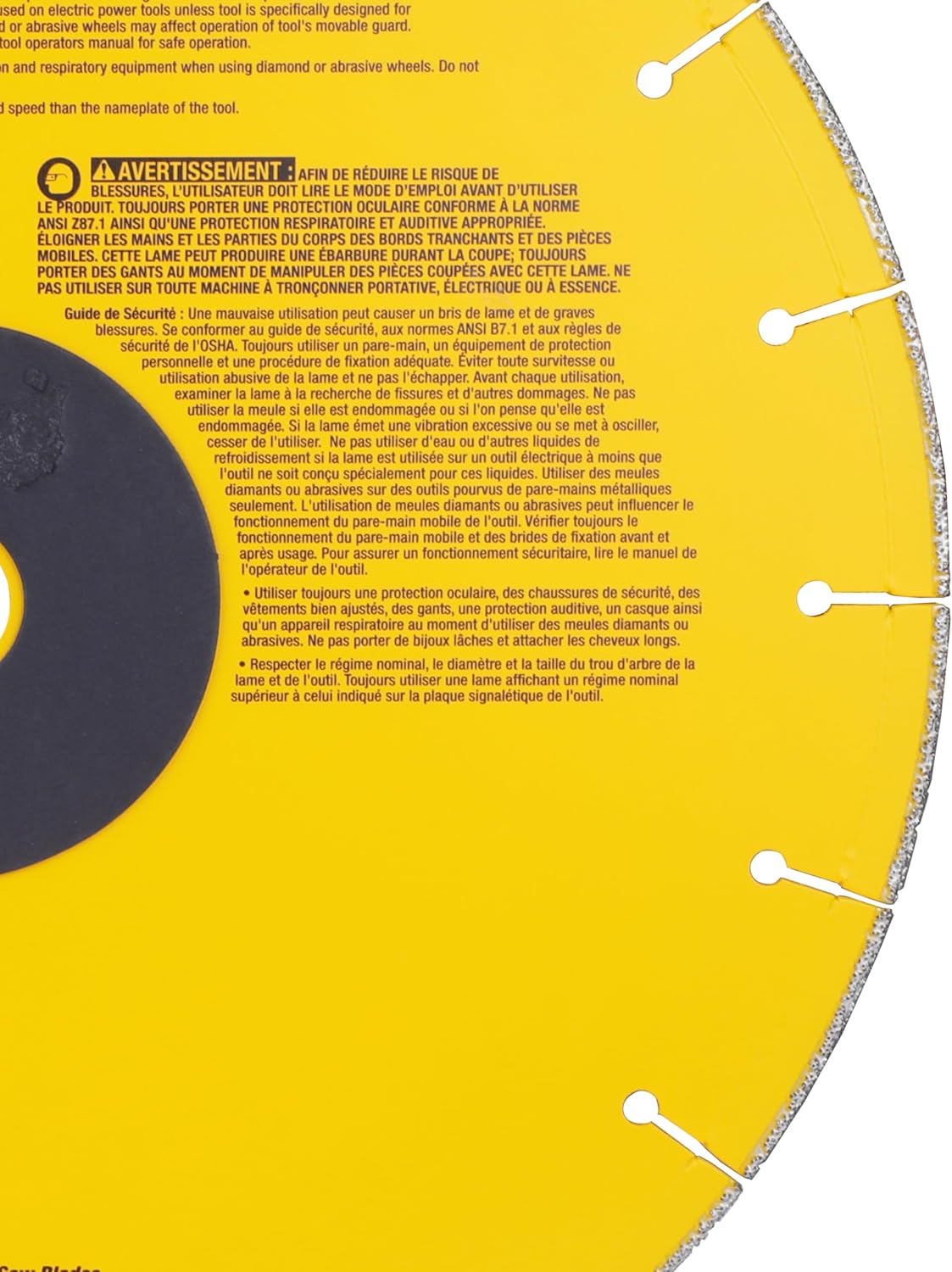 A macro close-up view of the rear side of the DeWalt metal cutting wheel, focusing on the yellow rim expansion slots and extensive French safety warnings and operator instructions printed in white text on the core housing.