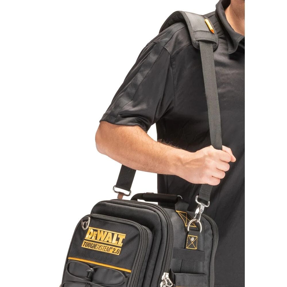 A person carrying the DeWalt compact tool bag hands-free over their shoulder using the adjustable padded strap, which features a small slot holding a pencil.
