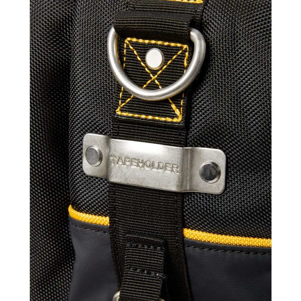 Extreme close-up of the metal tape measure clip riveted to the black fabric side of the bag, explicitly engraved with the word TAPEHOLDER, positioned directly below a metal D-ring.