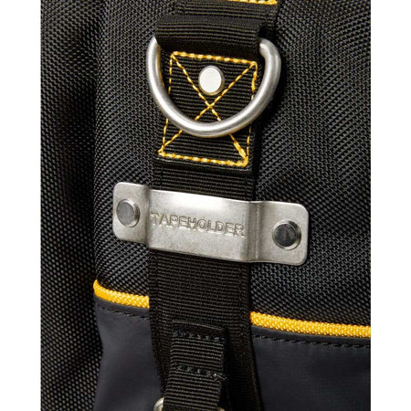 Extreme close-up of the metal tape measure clip riveted to the black fabric side of the bag, explicitly engraved with the word TAPEHOLDER, positioned directly below a metal D-ring.