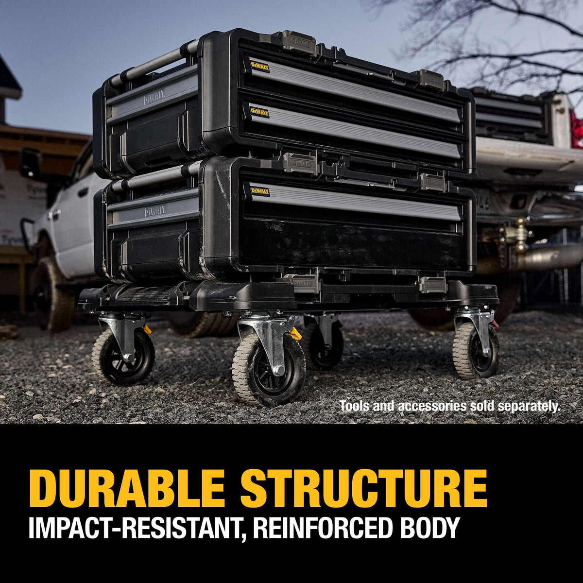 An outdoor jobsite application photo displaying two DEWALT ToughSystem 2.0 DXL drawer units stacked and locked together on top of a black four-wheeled rolling dolly trolley over a gravel ground workspace, with a pickup truck in the background and a lower text callout reading DURABLE STRUCTURE IMPACT-RESISTANT, REINFORCED BODY.