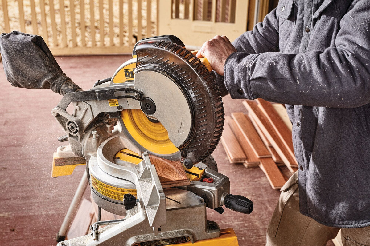 Woodworker trimming a hardwood flooring plank using the DeWalt DWS713 10-inch miter saw equipped with a carbide blade.
