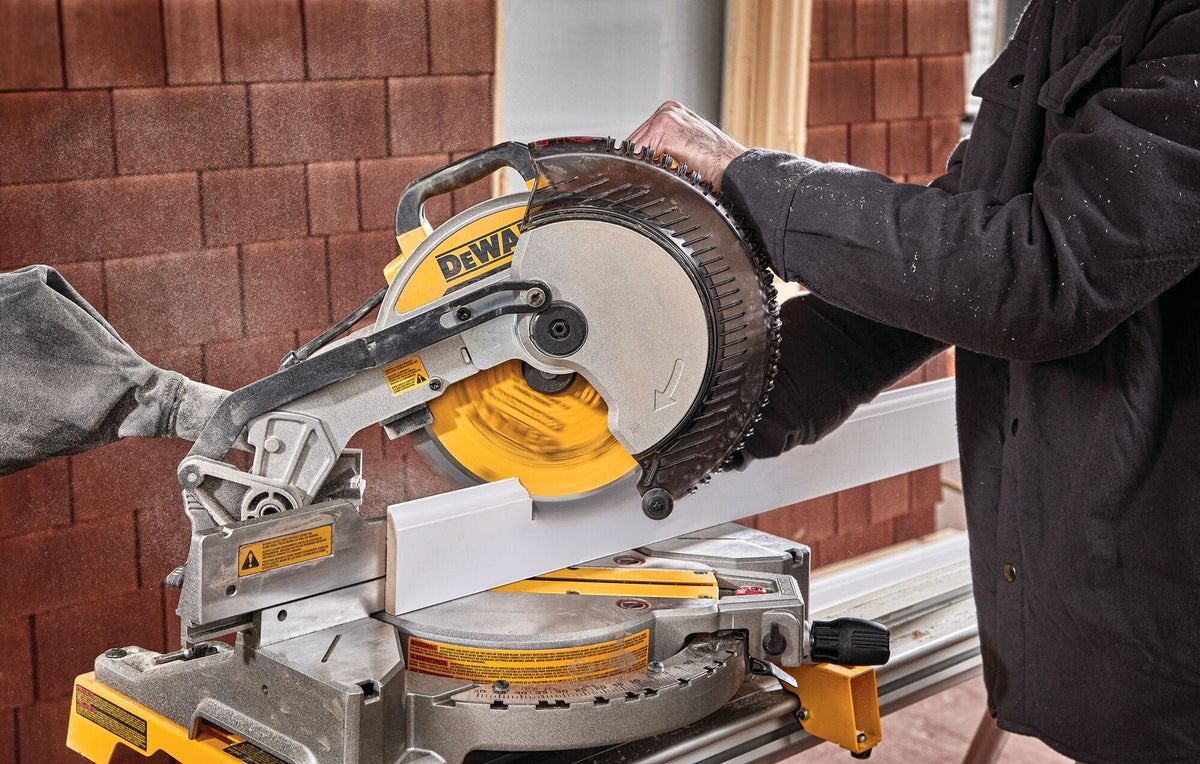Carpenter making a bevel angle cut on white crown molding with the DeWalt DWS713 miter saw supported by tall sliding fences.