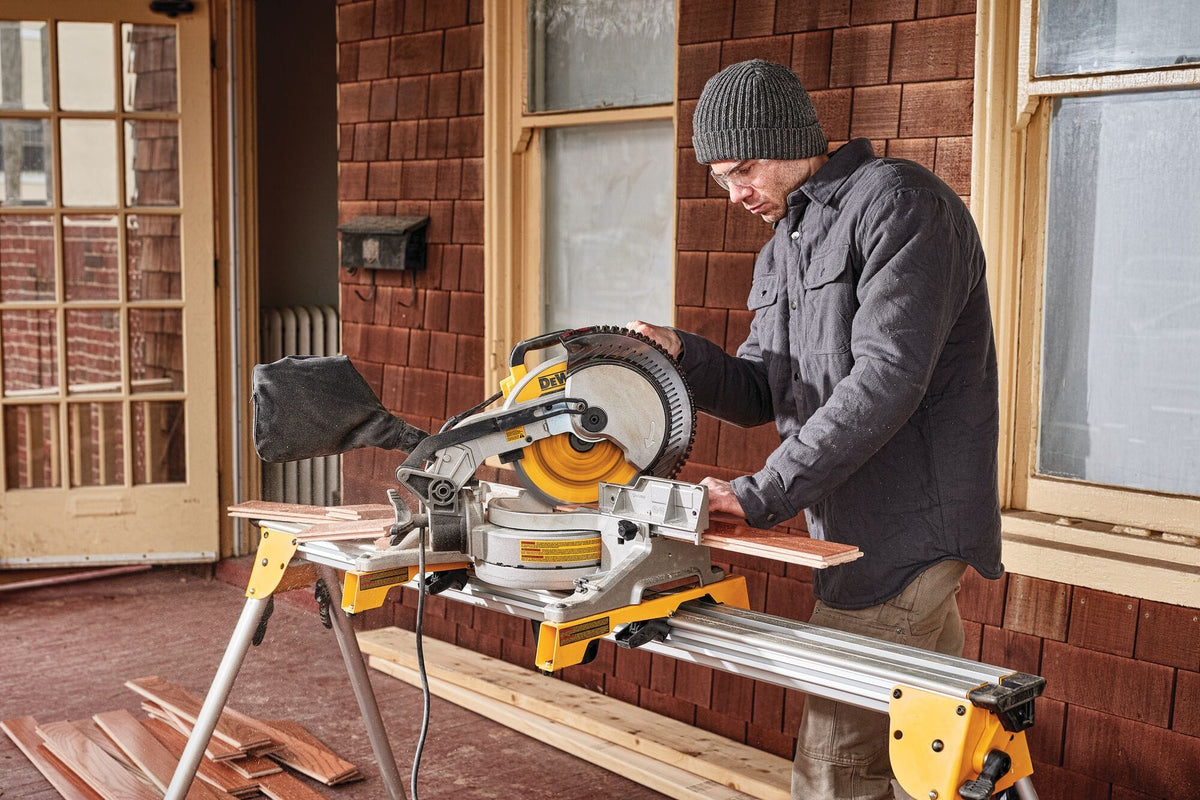 Trim carpenter crosscutting engineered hardwood planks on a portable stand using the DeWalt DWS713 15 Amp compound miter saw.