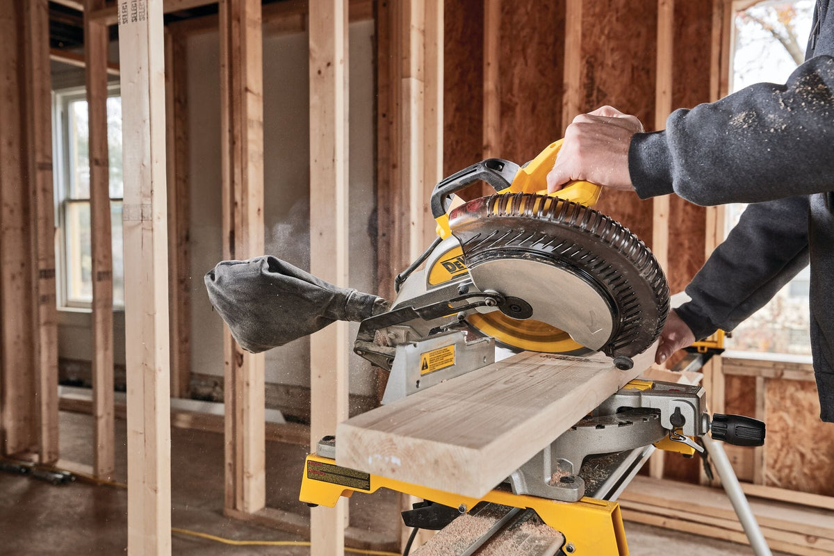 Contractor crosscutting a 2x6 dimensional lumber board on a jobsite using the DeWalt DWS713 10-inch single-bevel compound miter saw.