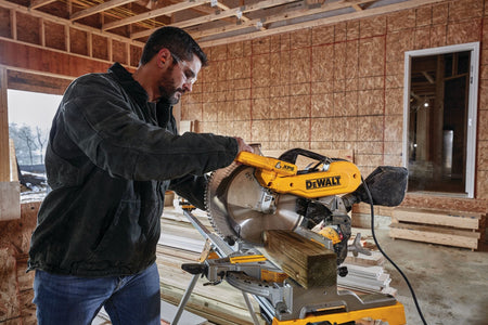 Framer crosscutting pressure-treated 4x4 dimensional lumber using the 12-inch blade on the DeWalt DWS716 compound miter saw.