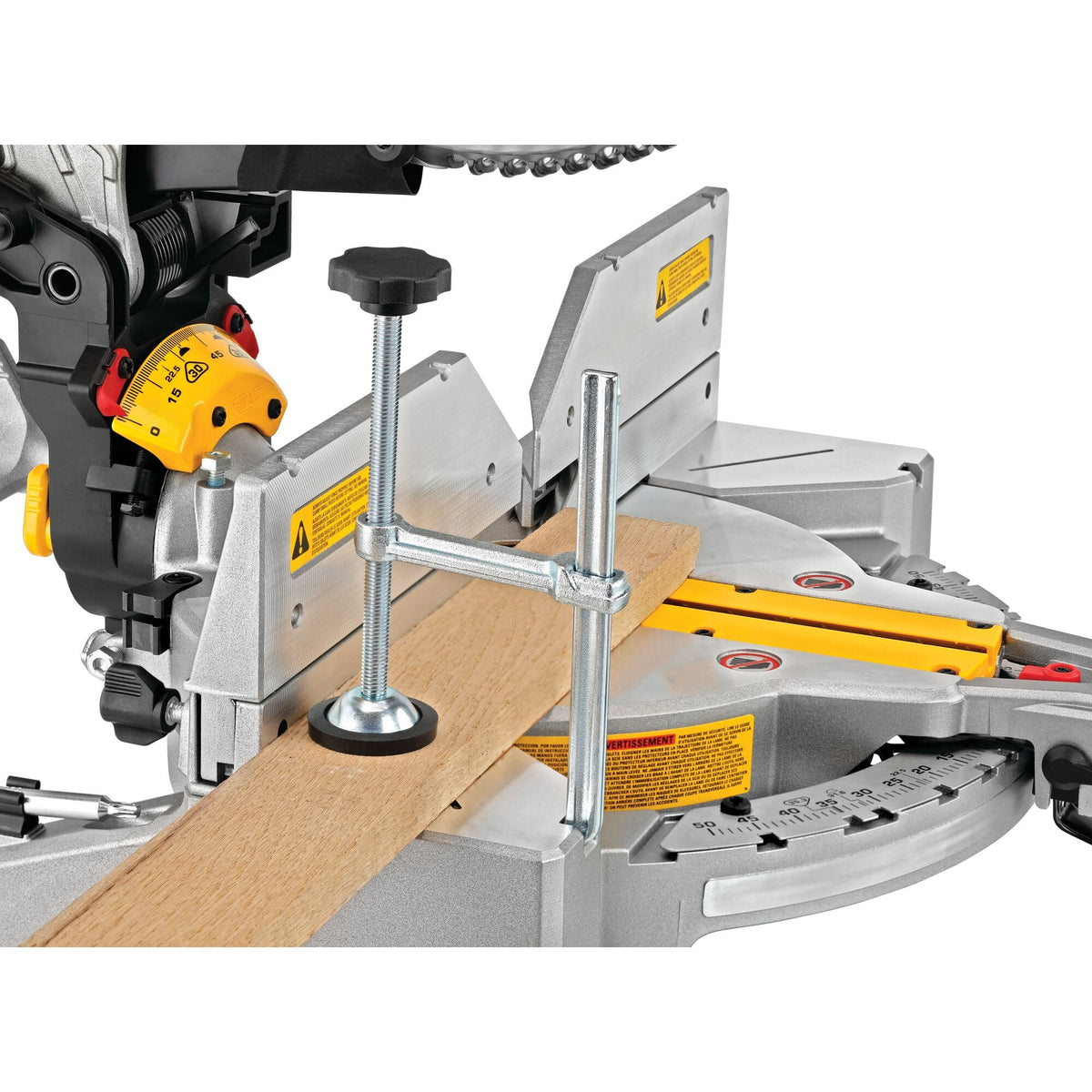 Vertical material clamp holding a hardwood board securely against the aluminum base fence on the DeWalt DWS716 miter saw.