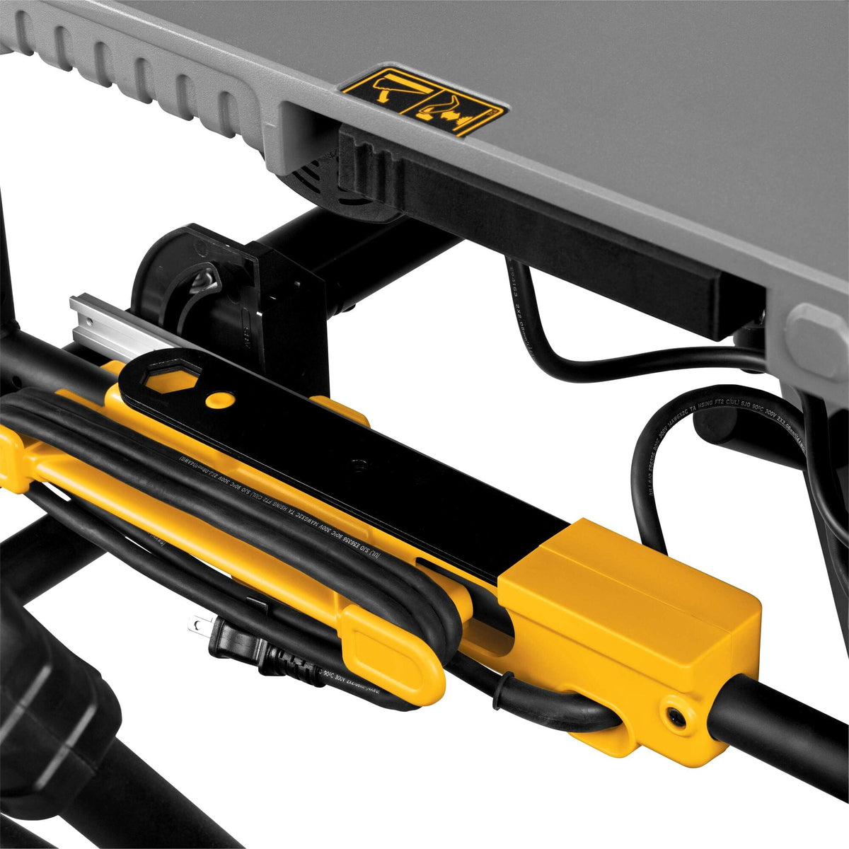 Under-table storage bracket on the DeWalt DWE7491RS table saw holding the coiled 120V power cord and blade wrenches.