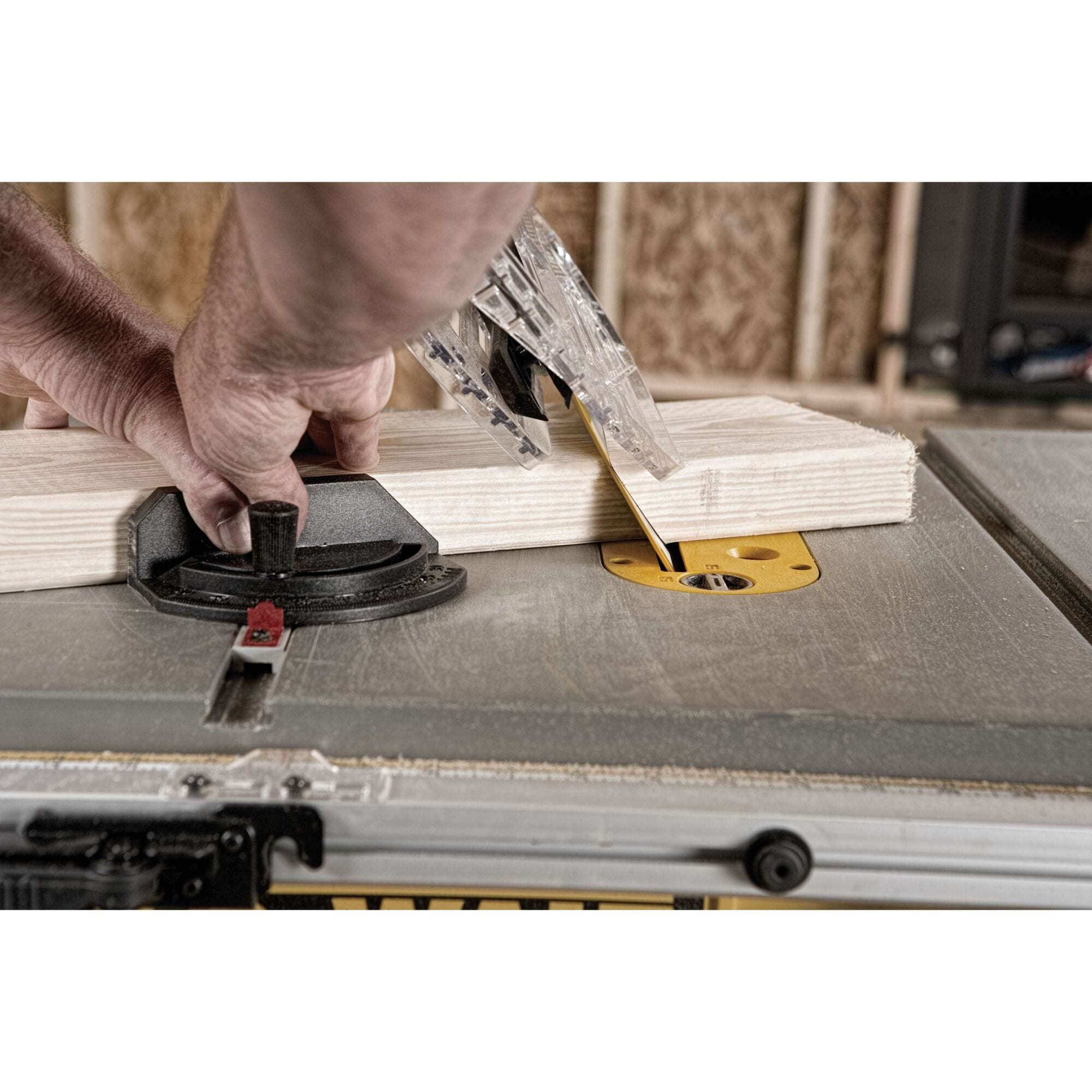 Woodworker guiding a dimensional lumber board through a bevel angle cut on the DeWalt DWE7491RS table saw using the miter gauge.