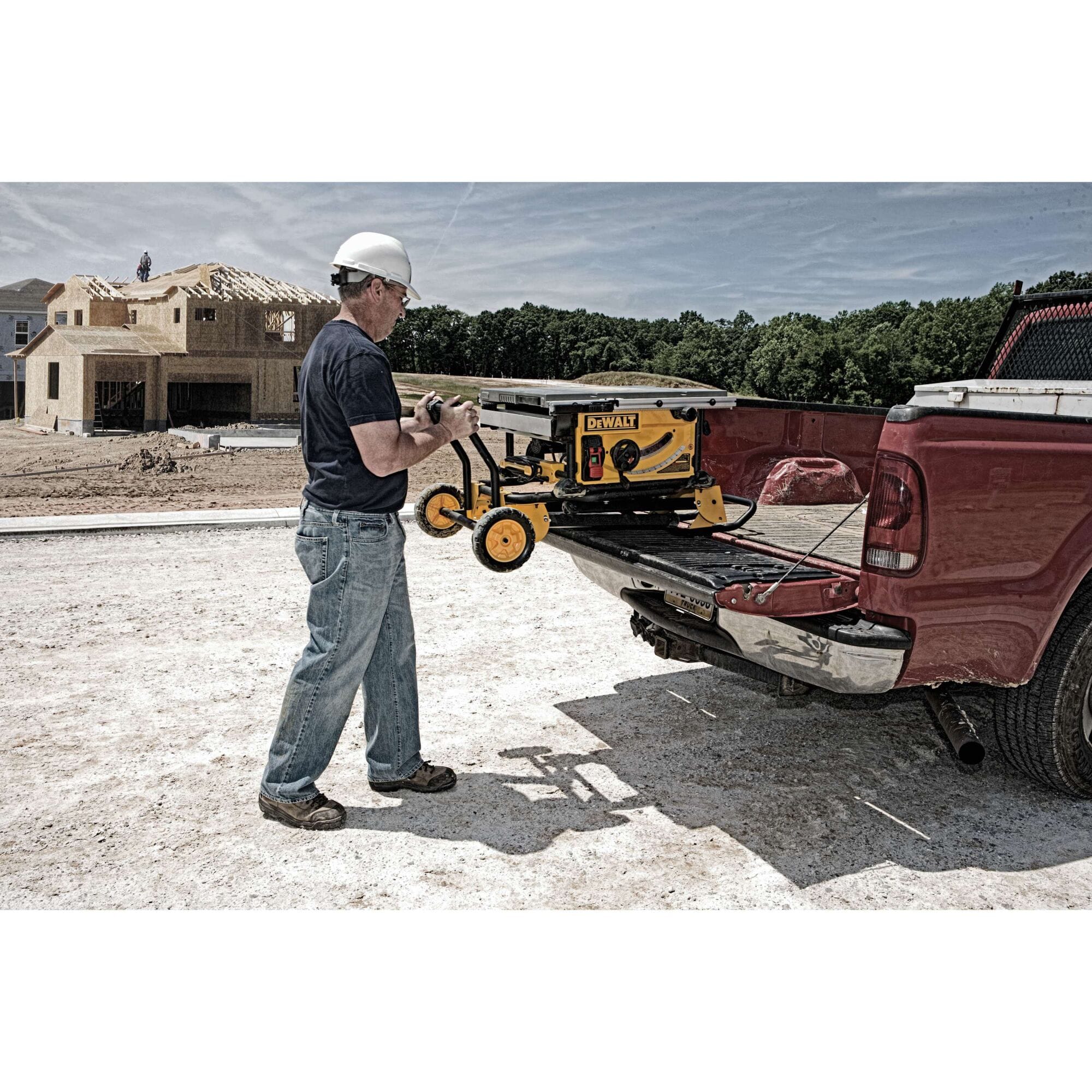 Contractor loading the collapsed DeWalt DWE7491RS jobsite table saw into a pickup truck bed using the integrated rolling stand handles.
