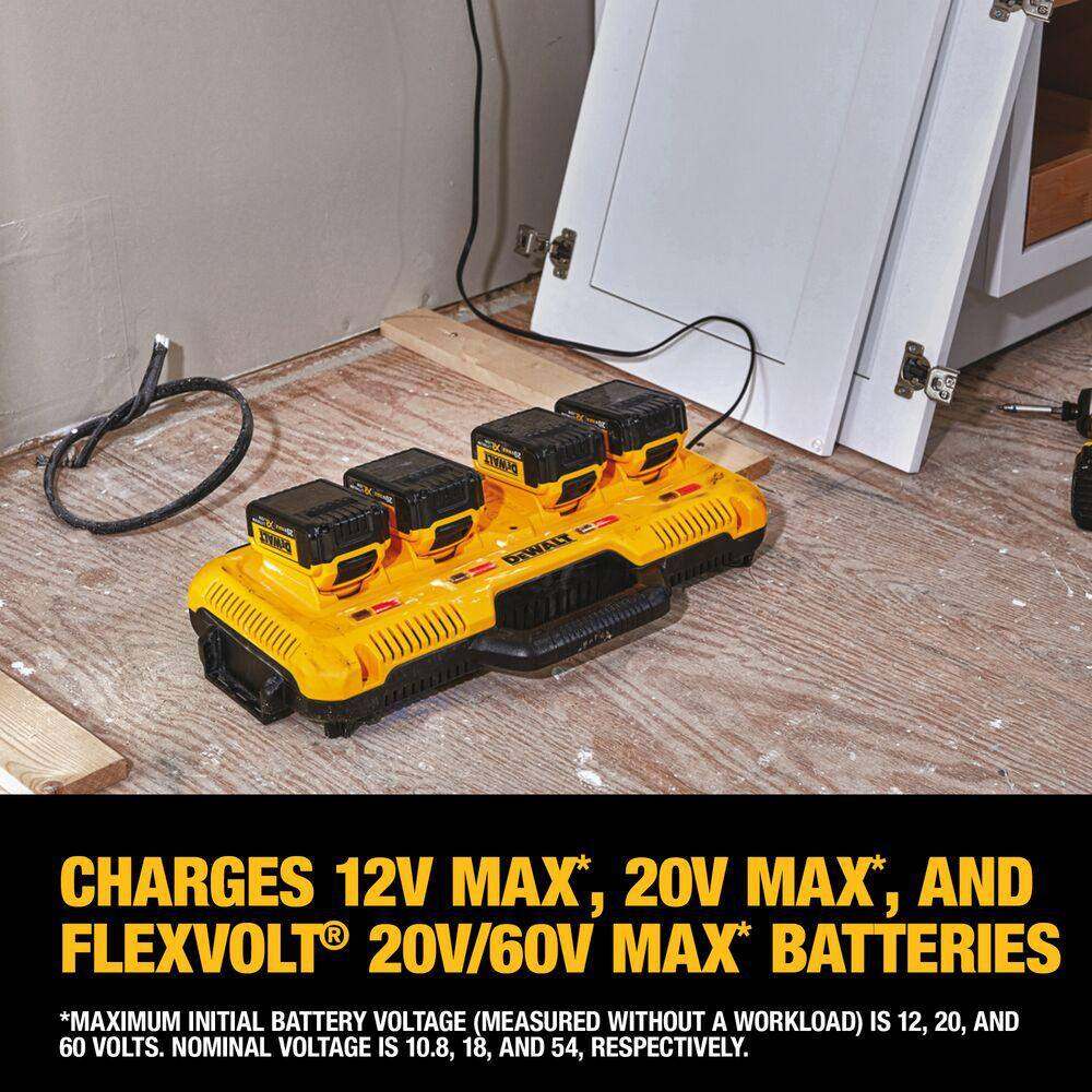 The Dewalt DCB104 charger sitting on a residential construction floor charging four batteries simultaneously; text overlay states it charges 12V MAX, 20V MAX, and FlexVolt 20V/60V MAX batteries.