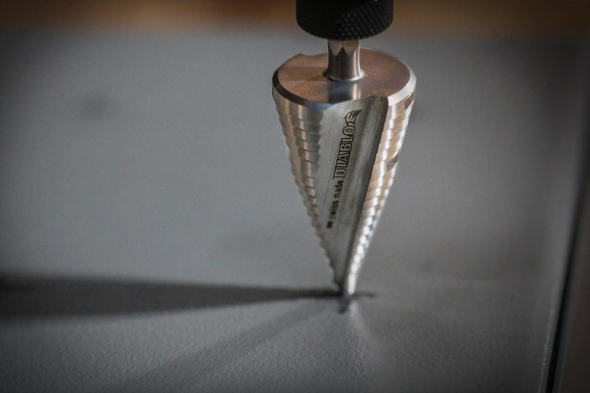 Macro action shot of a Diablo dual flute step drill bit beginning a precise cut into a metal surface, demonstrating the non-slip split point tip.
