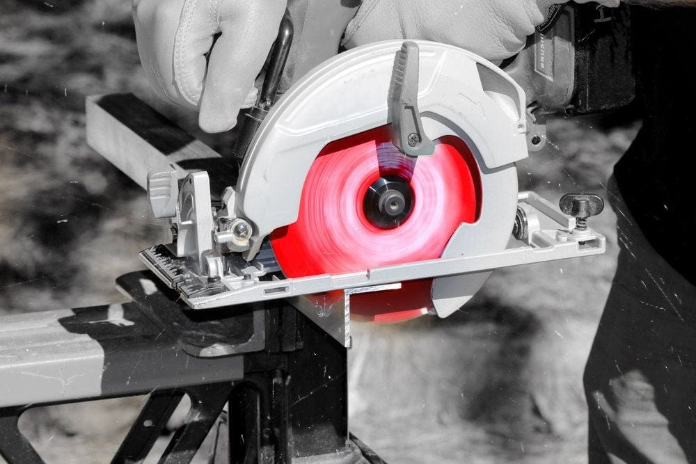 An action photograph showcasing a Diablo circular saw blade making a precise, clean cut through an industrial aluminum profile secured to a jobsite stand. The image demonstrates the blade’s ability to produce burr-free finishes in non-ferrous metals.