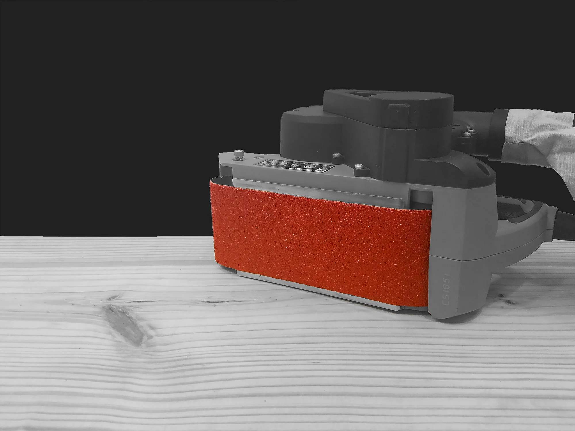 Industrial portable belt sander equipped with a Diablo 36 grit zirconium sanding belt performing heavy stock removal and leveling on a large wood plank.